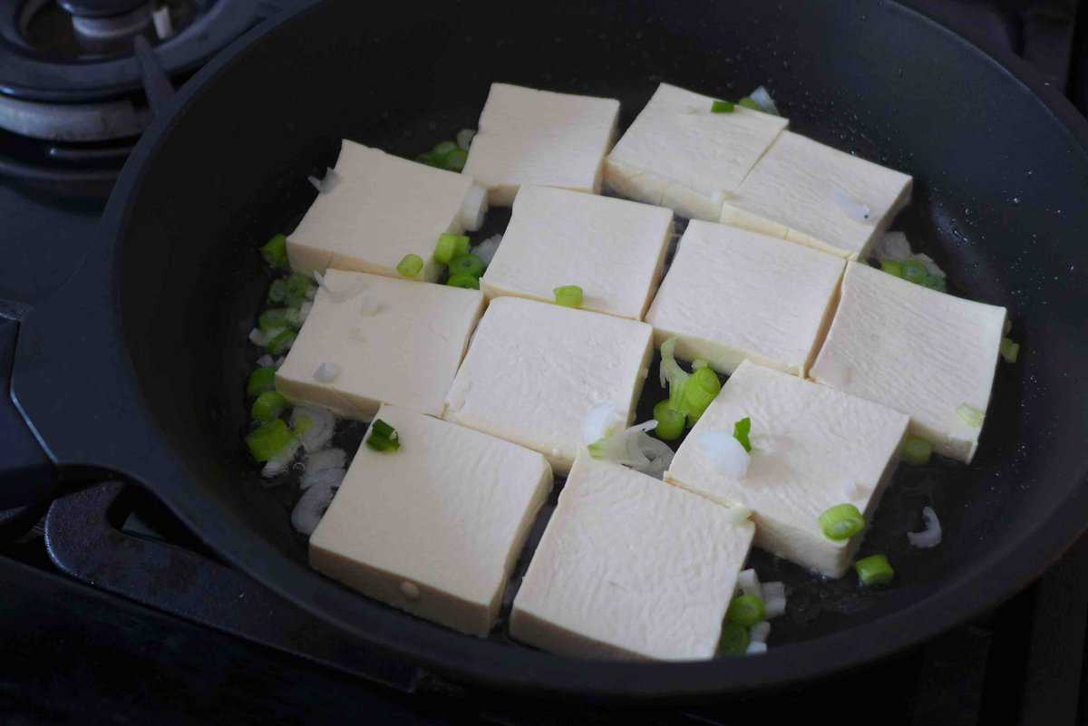 pan-frying tofu pieces.