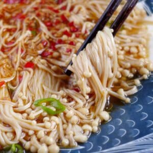 Chopsticks picking up steamed enoki mushroom