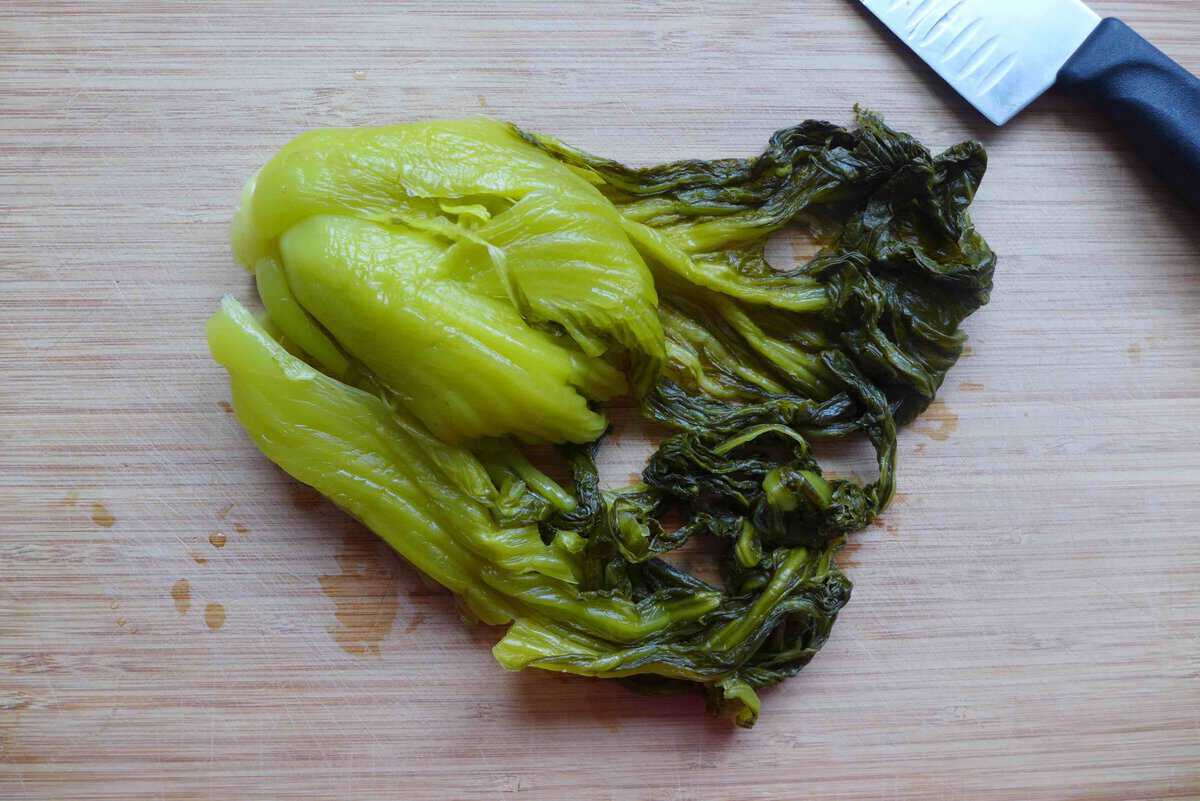 pickled mustard greens on a chopping board.