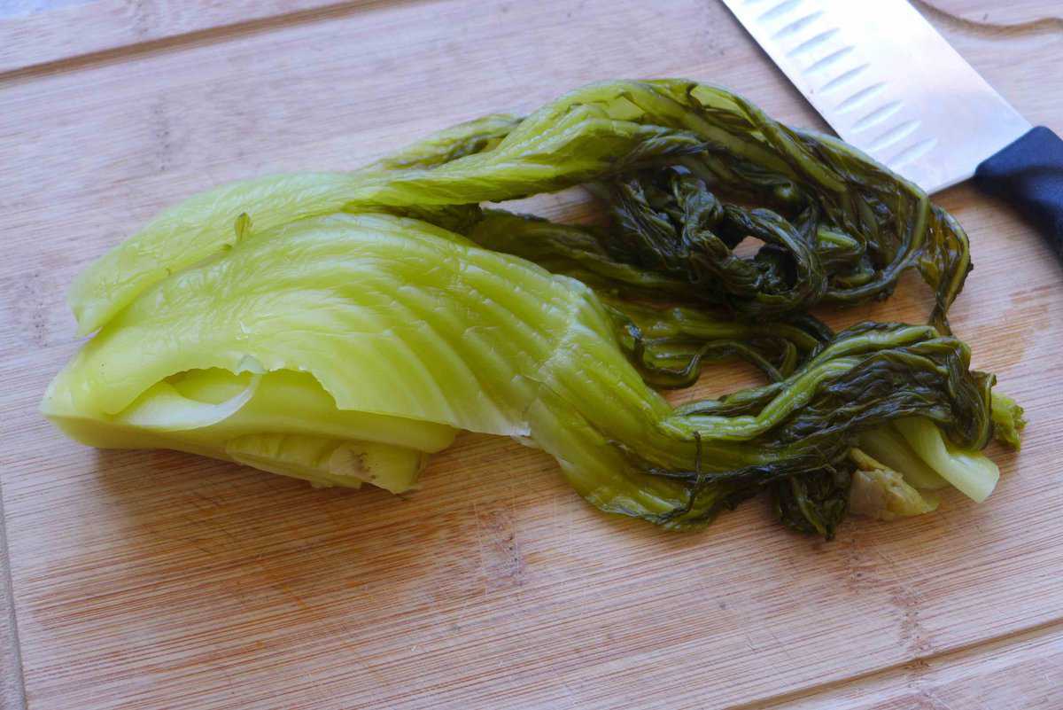 pickled mustard greens on a chopping board.