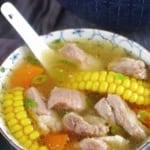 a small bowl of pork rib soup with corn and carrot.