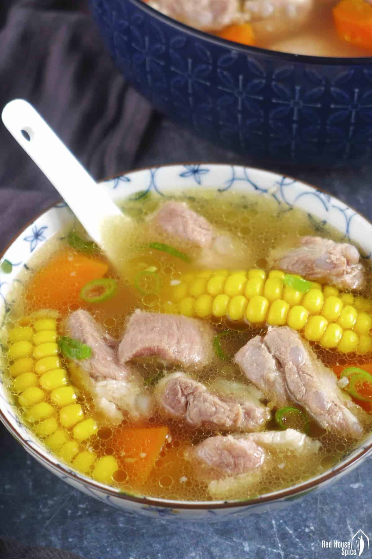 a small bowl of pork rib soup with corn and carrot.