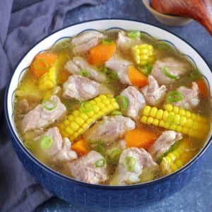 a big bowl of pork rib soup with corn and carrot.