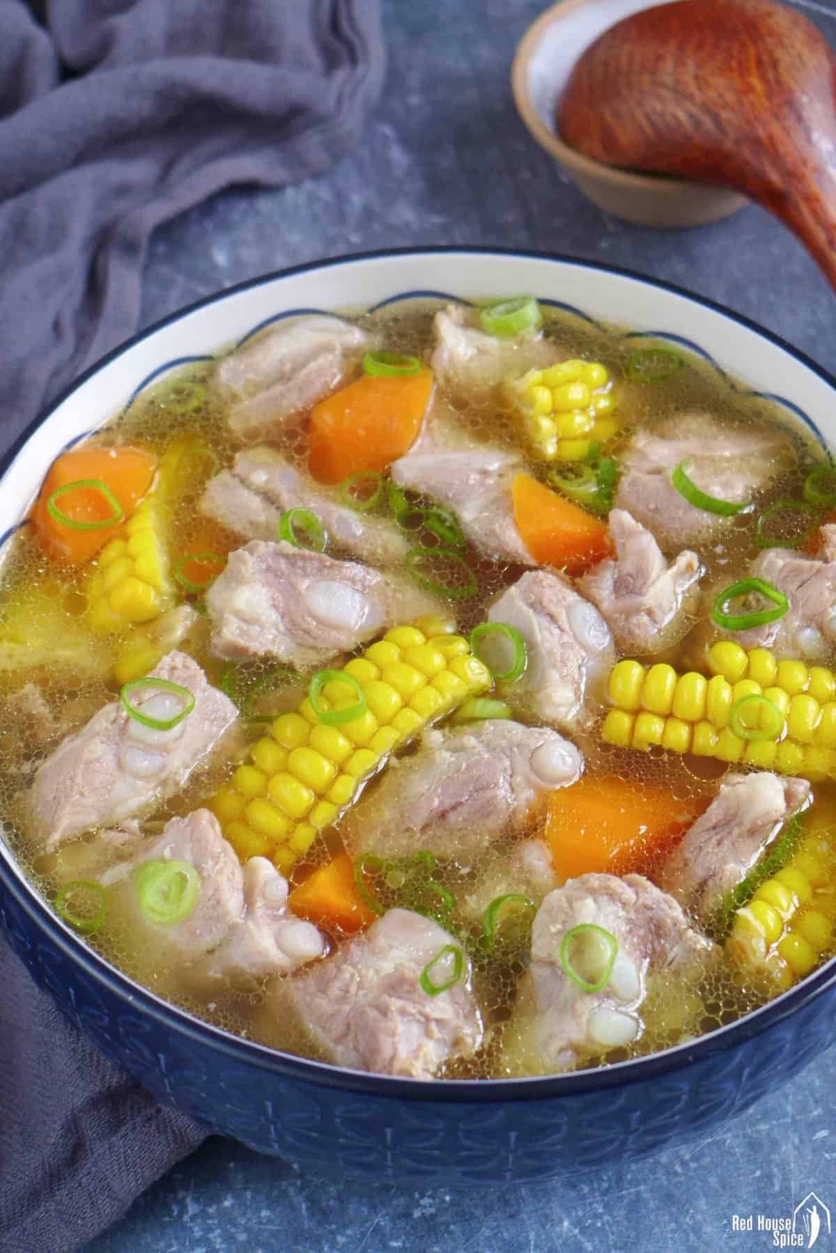 a big bowl of pork rib soup with corn and carrot.