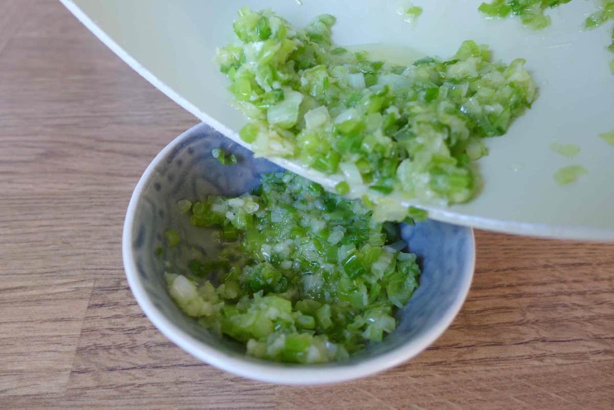 pouring fried scallions, ginger and garlic into a bowl