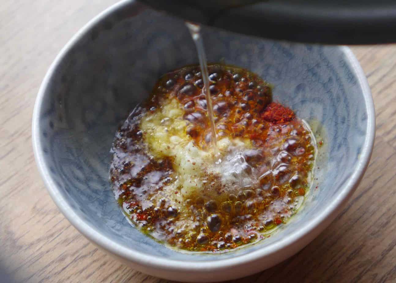 pouring hot oil over spices