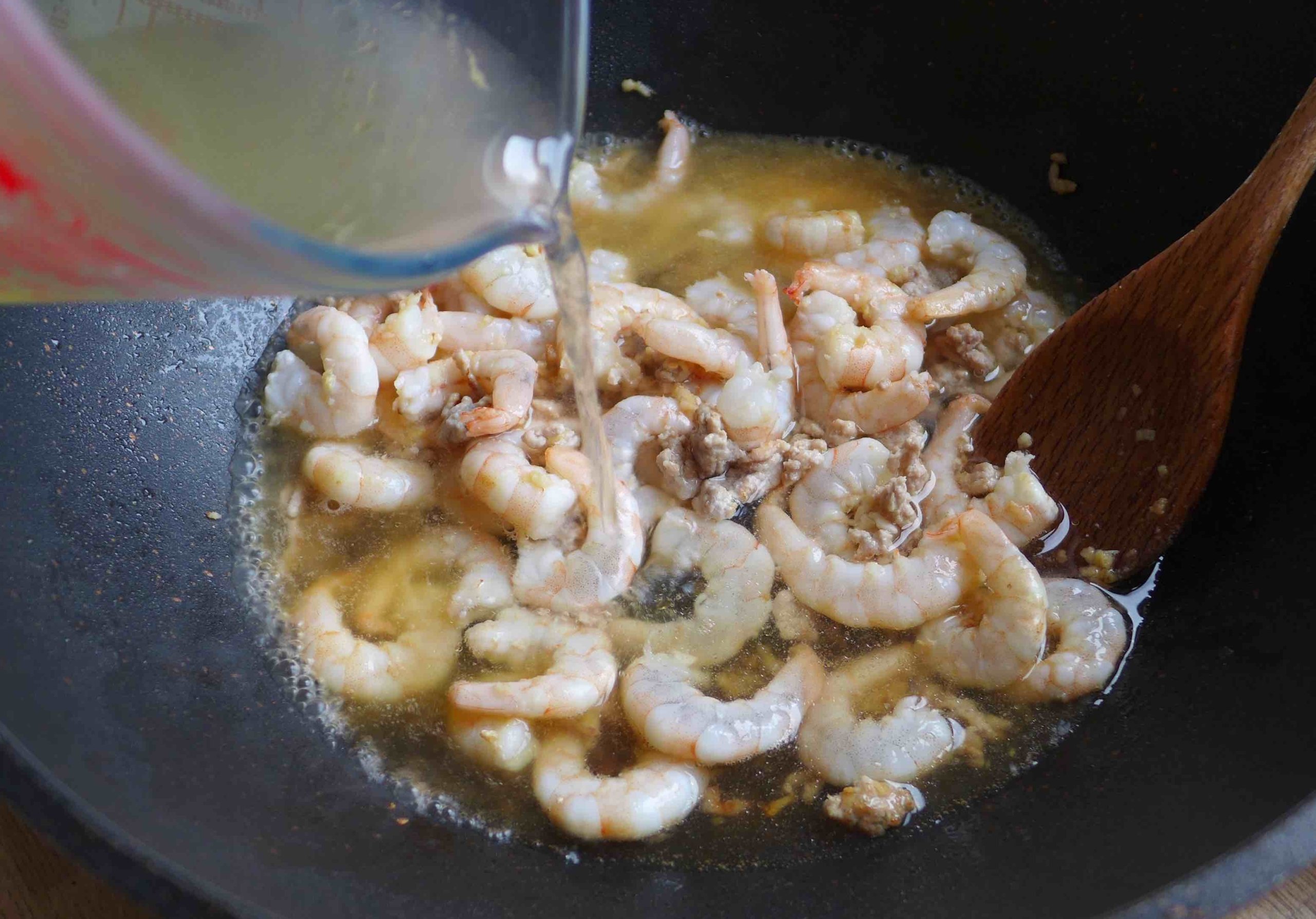 adding broth to shrimp.