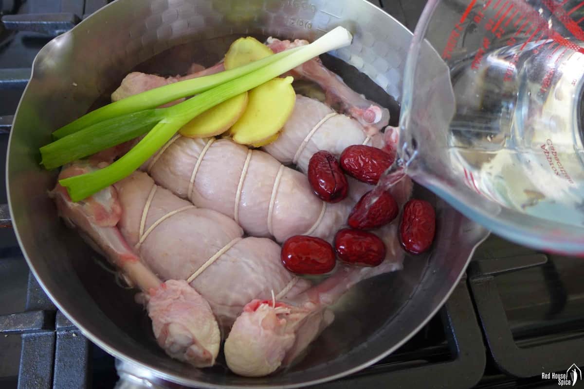 pouring water over chicken in a pot