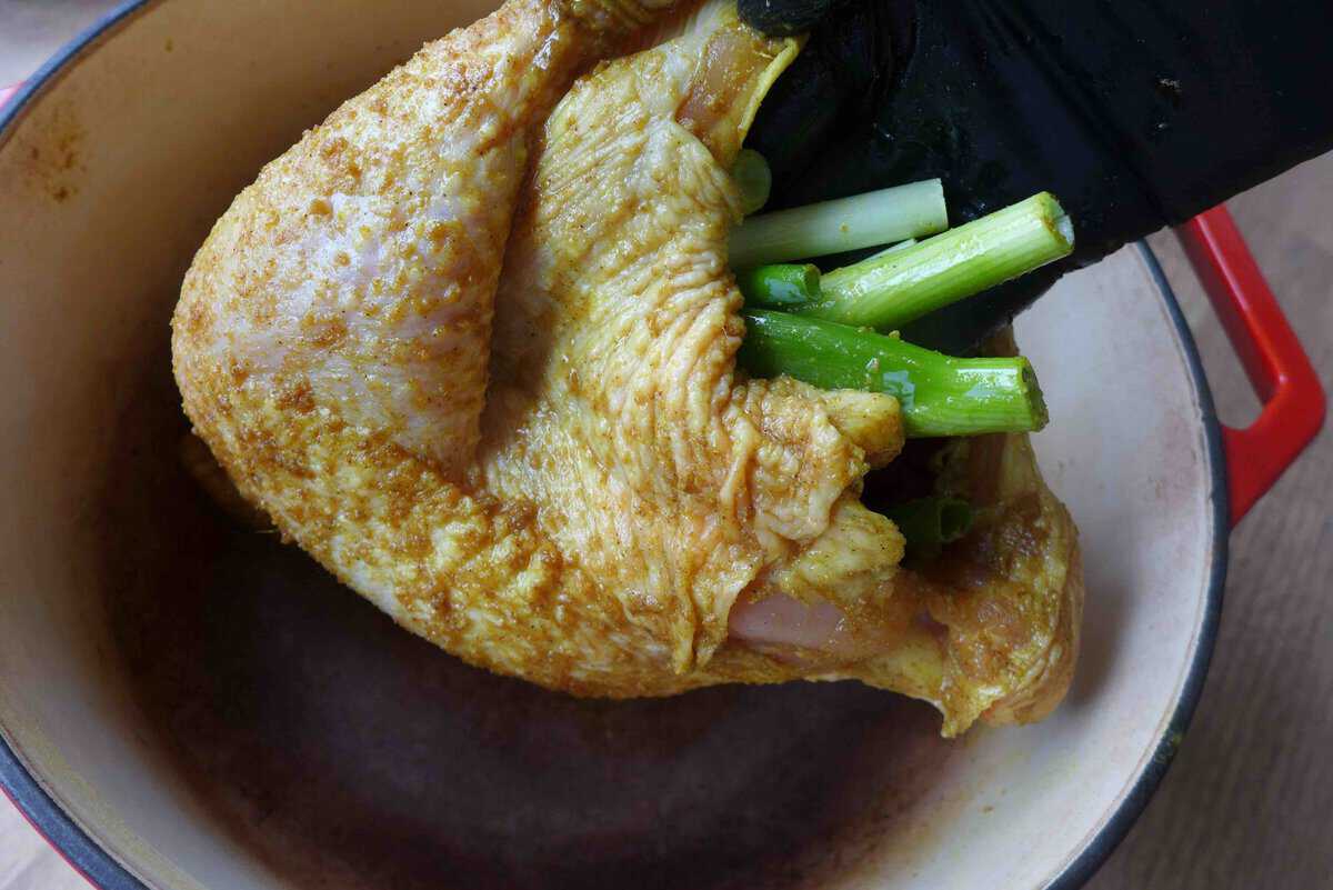 putting ginger and scallions inside chicken cavity.