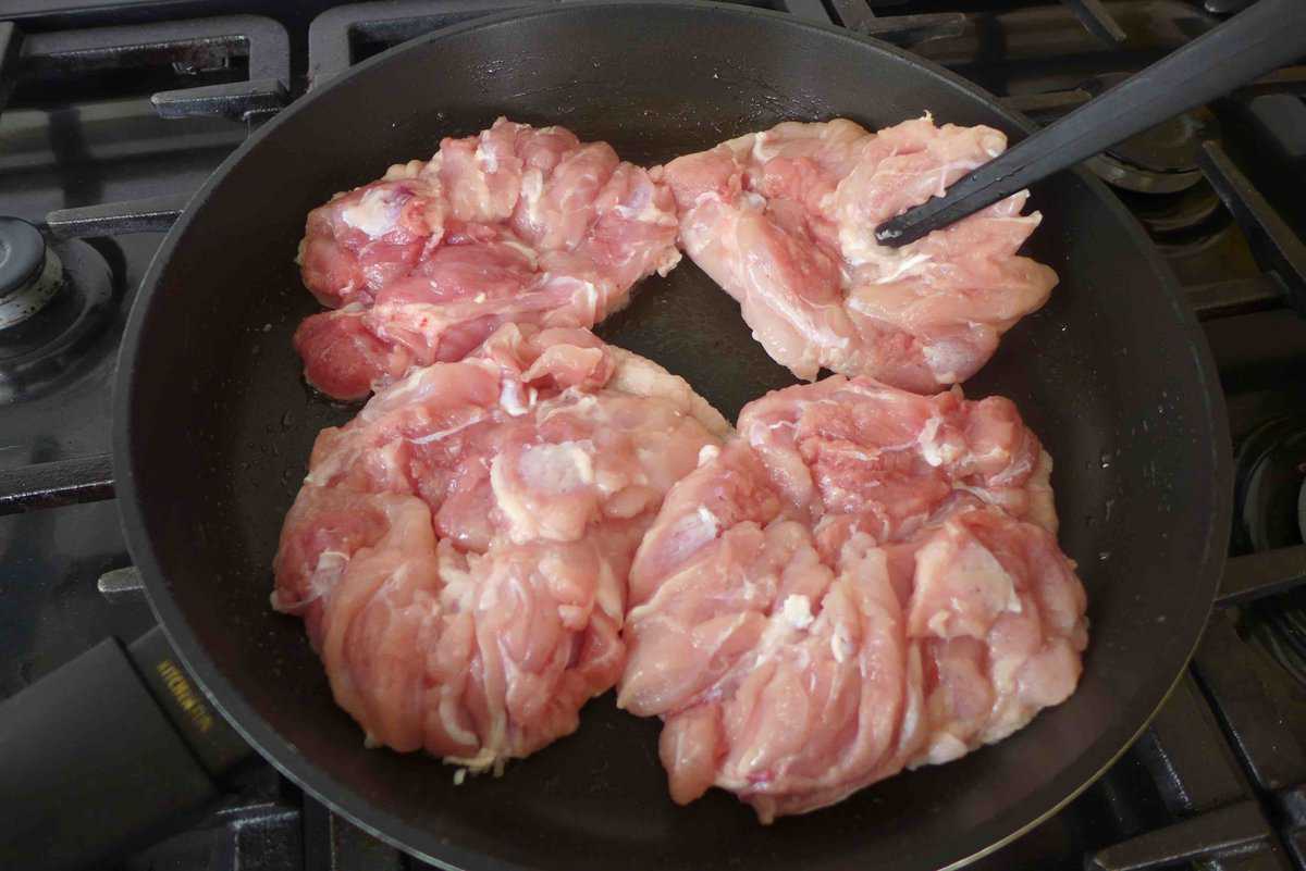 putting raw chicken into skillet.
