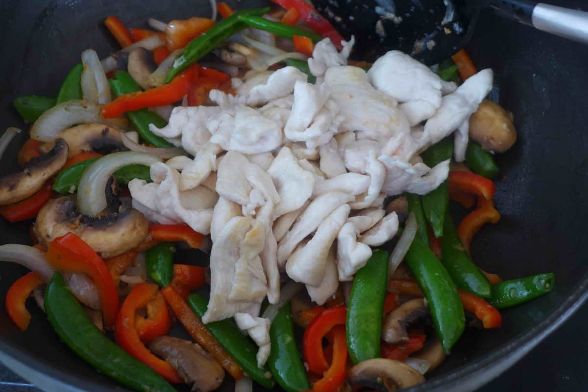 adding chicken to vegetables.