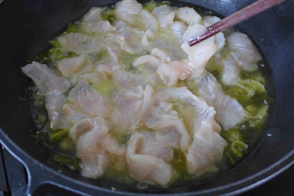 putting fish slices into broth.