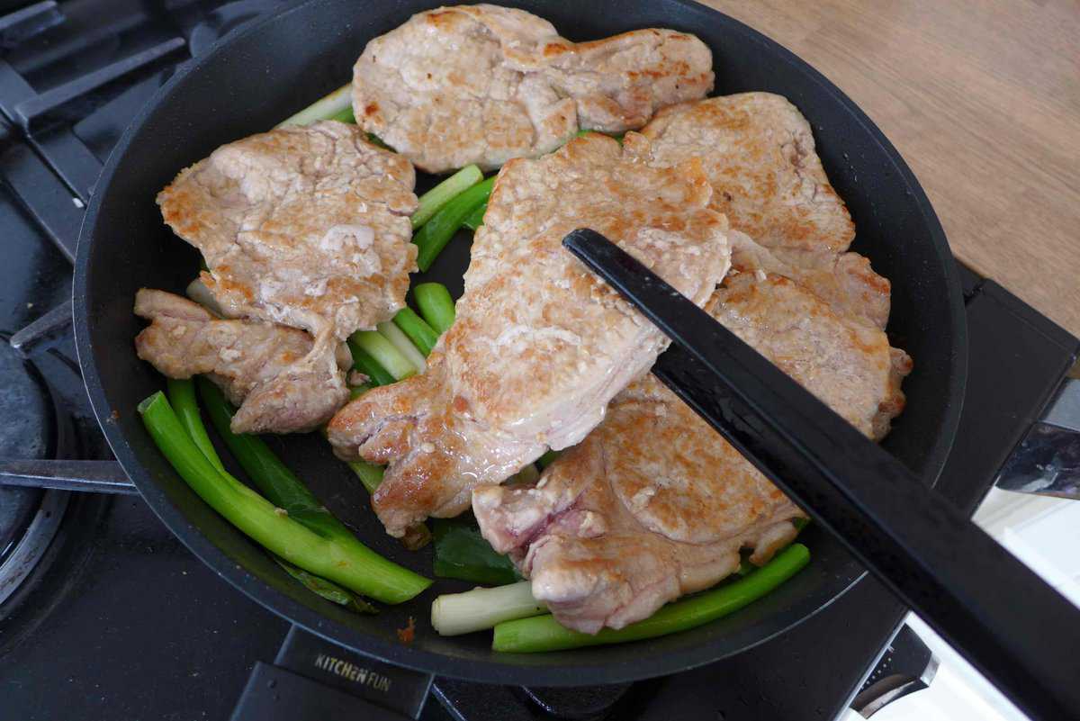 putting pork chops over scallions.
