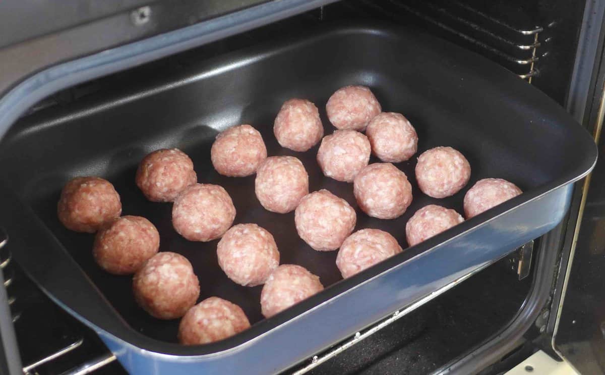 putting raw meatballs in the oven.