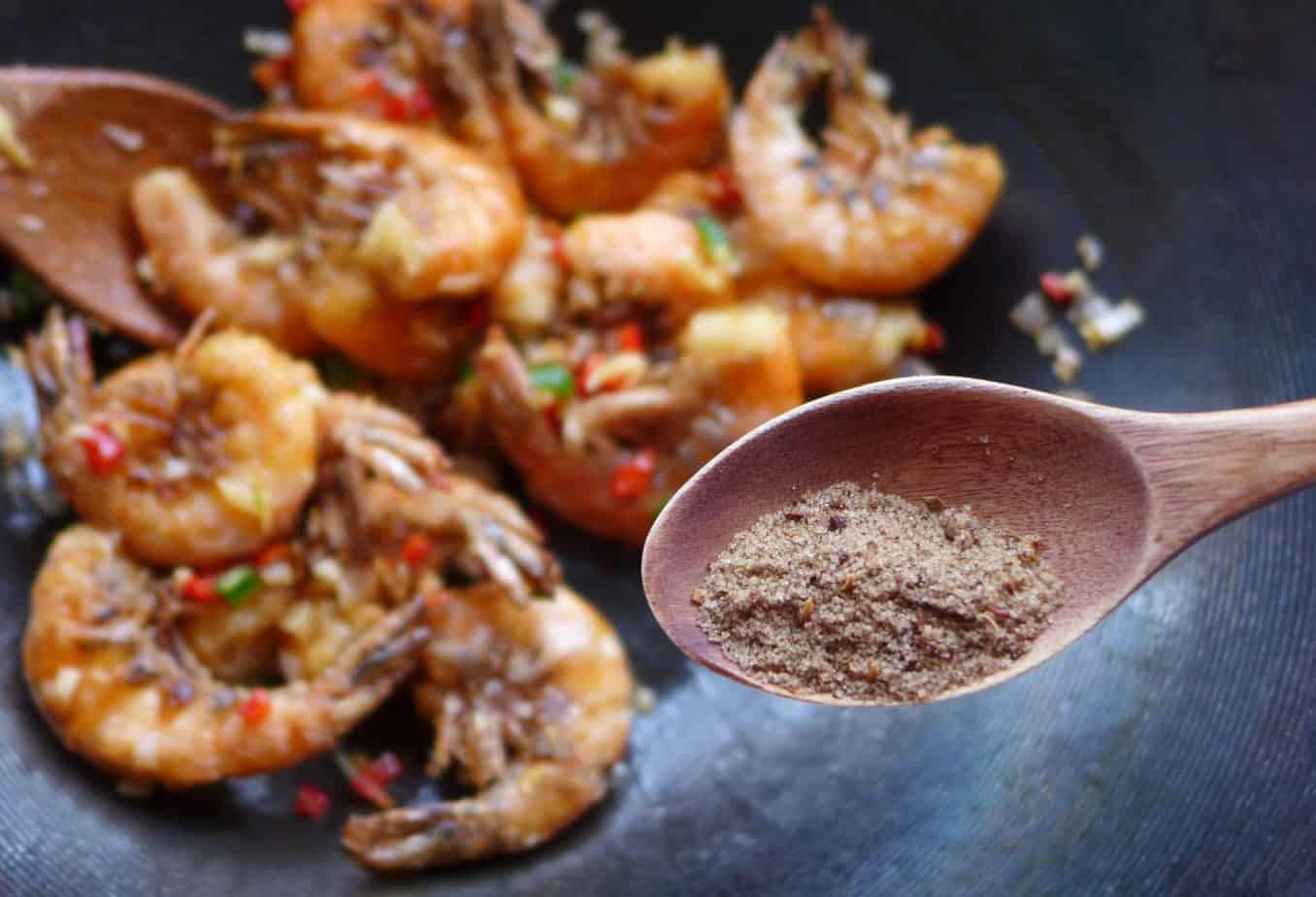 Putting salt and pepper seasoning over shrimp