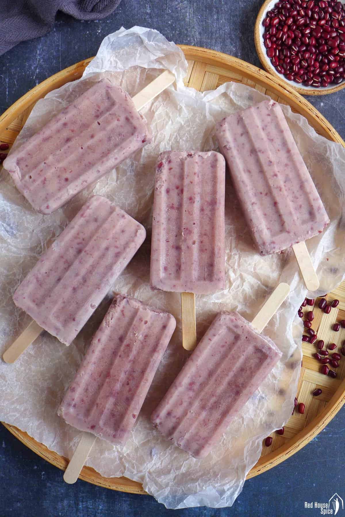 six red bean popsicles on a tray.