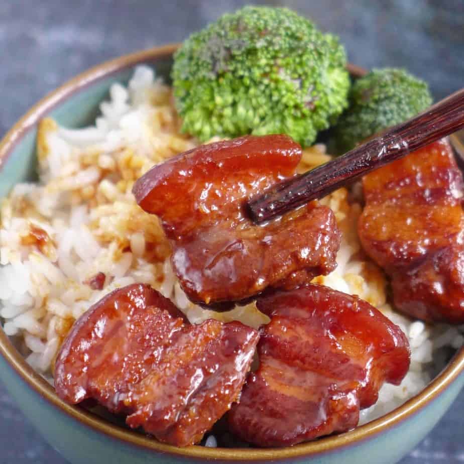 chopsticks picking up a pieces of braised pork belly
