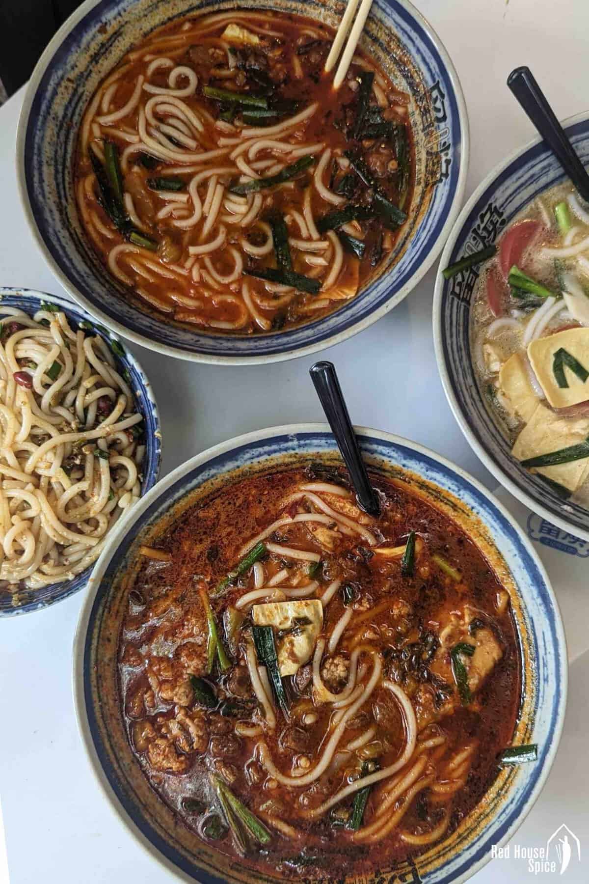Four bowls of rice noodle dishes at a Kunming food stand.