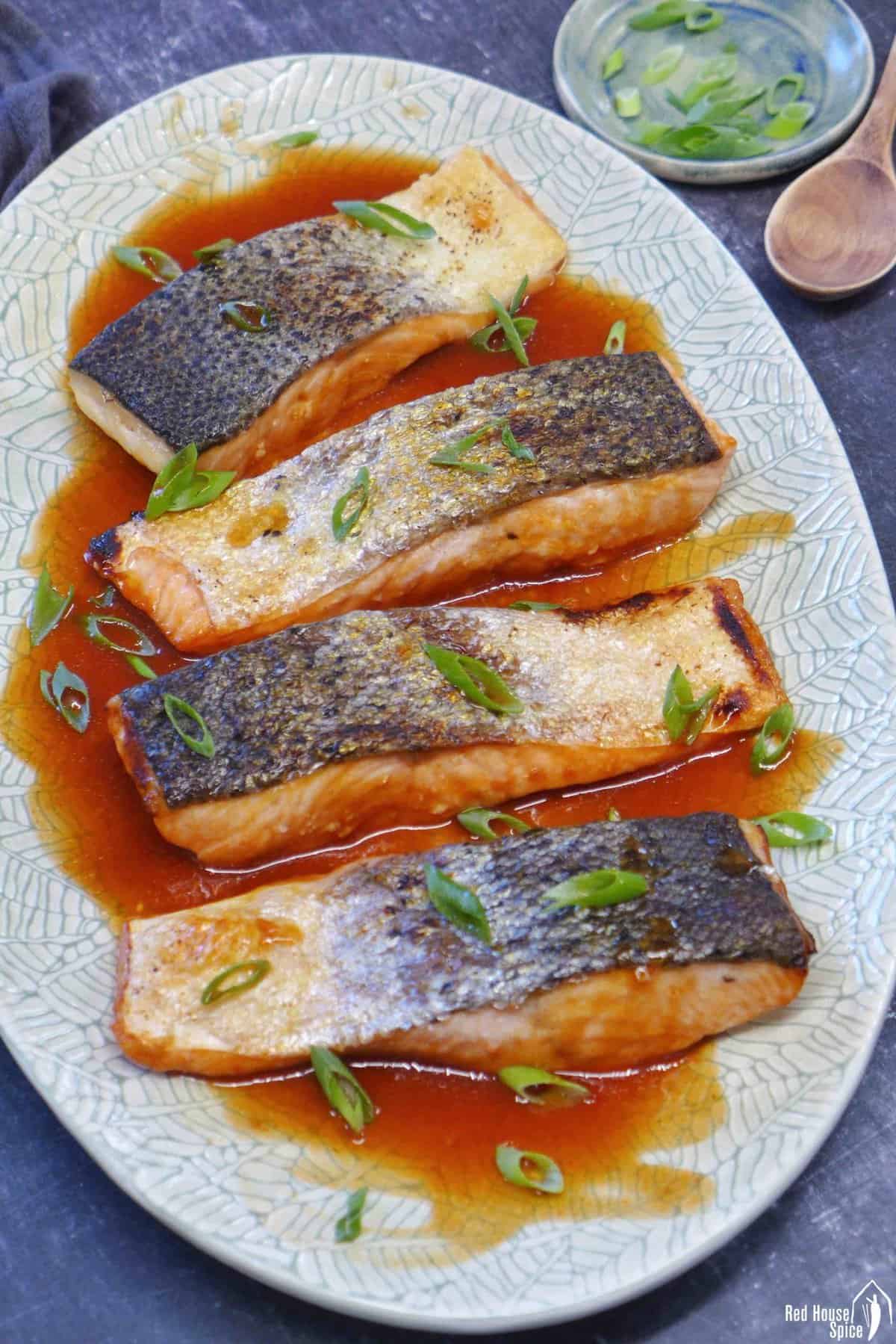 four pieces of roast salmon filets with sweet and sour sauce.