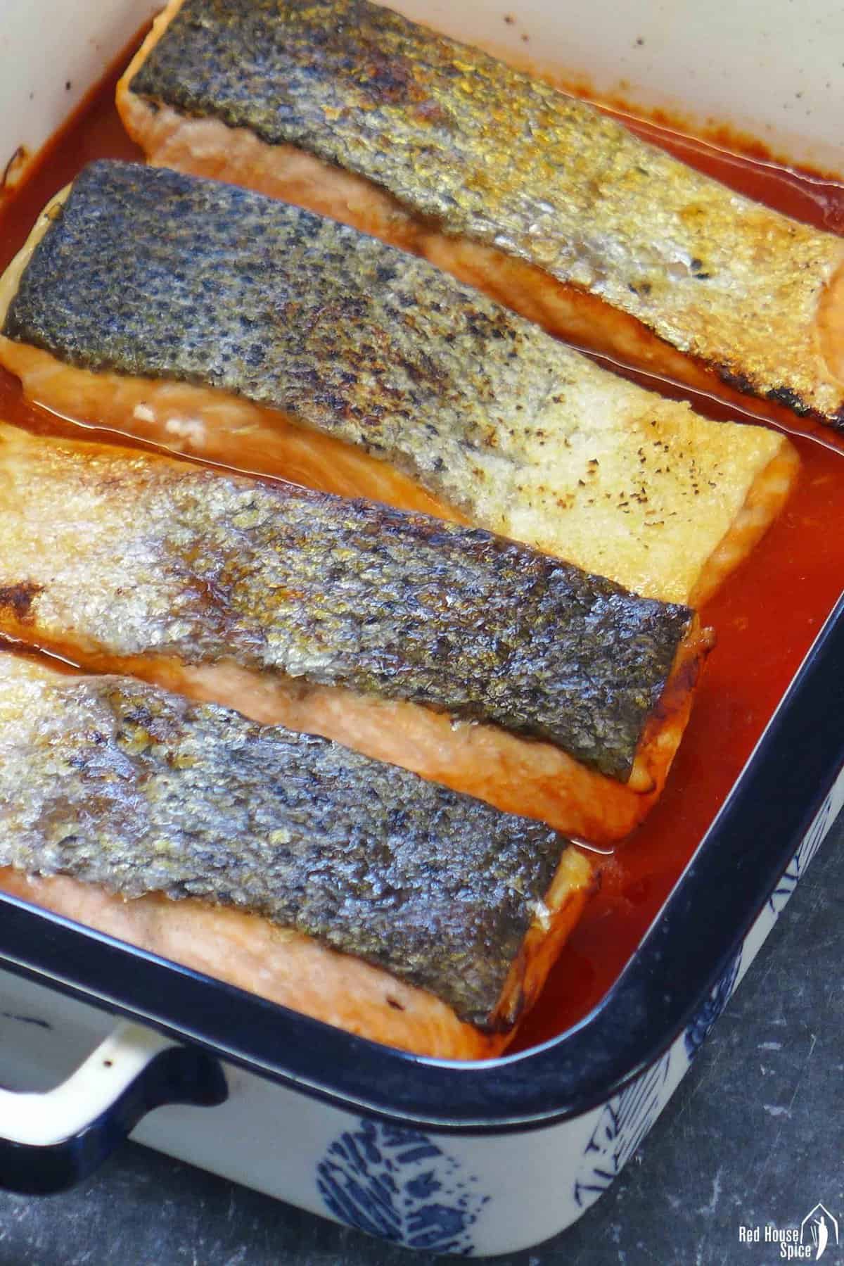 roast salmon filets with sauce in a roasting dish.