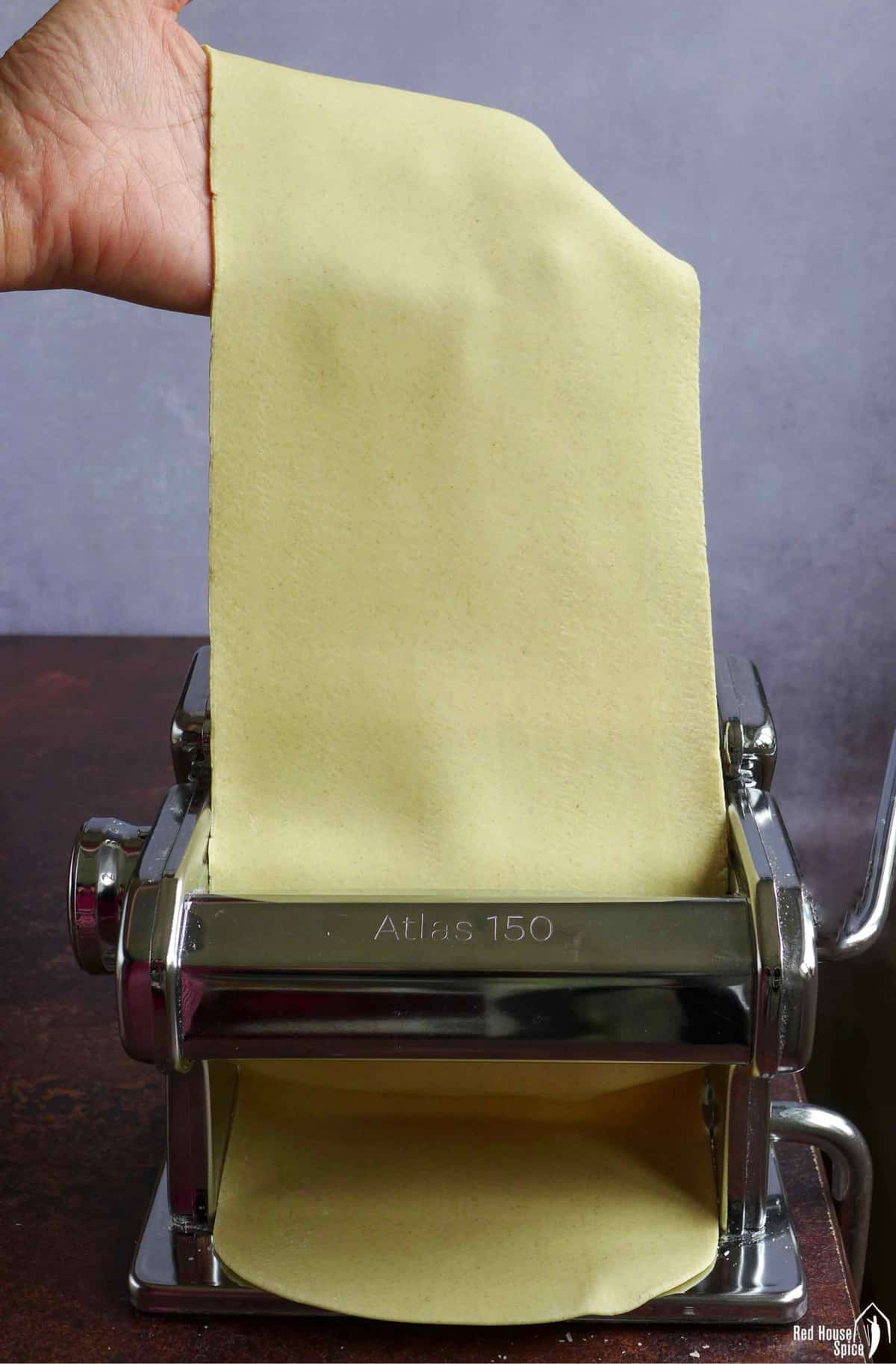 passing a piece of dough sheet through a pasta maker