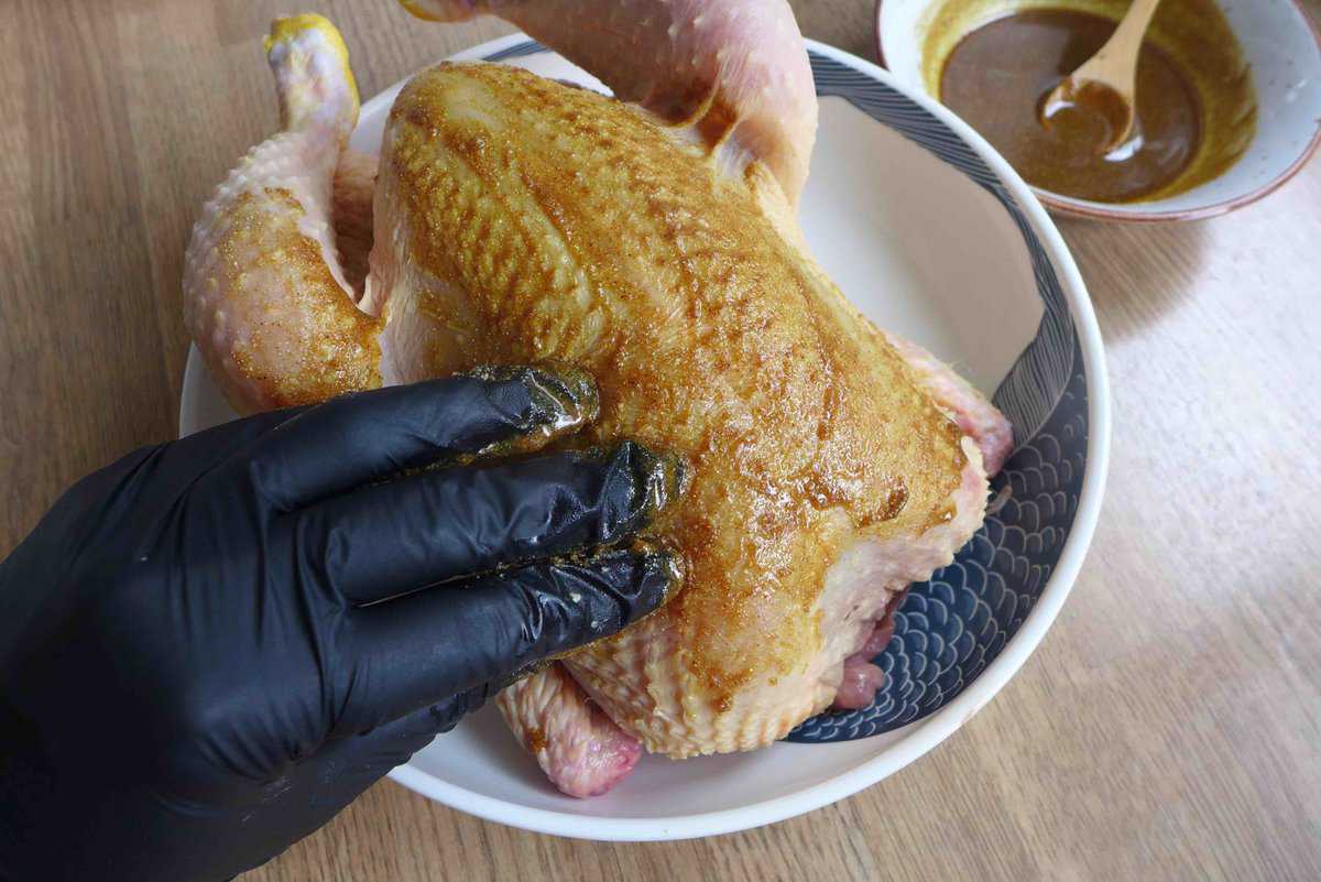 rubbing marinade over a whole chicken.