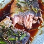 A pan fried salmon filet torn into two pieces.