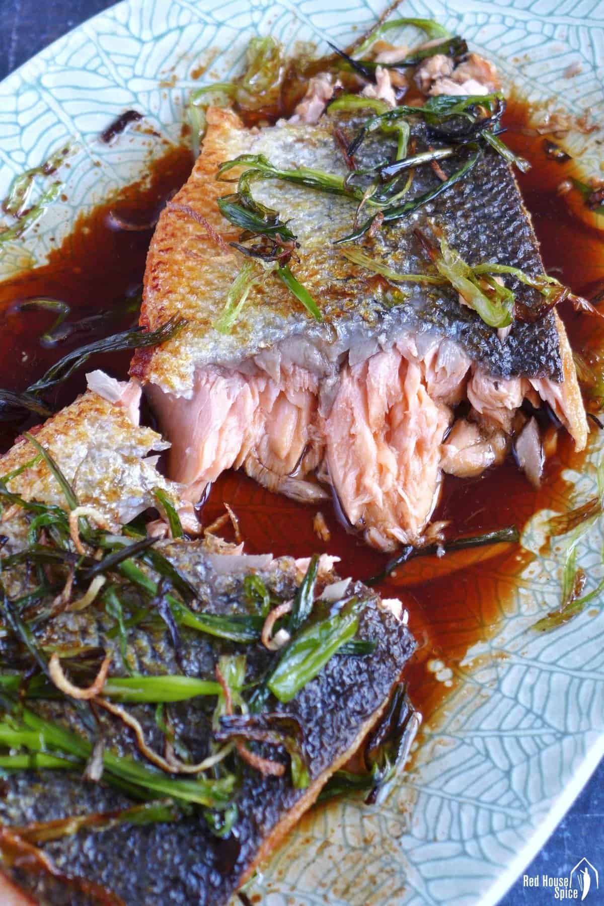 A pan fried salmon filet torn into two pieces.