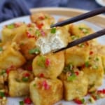 chopsticks picking up a piece of half eaten fried tofu