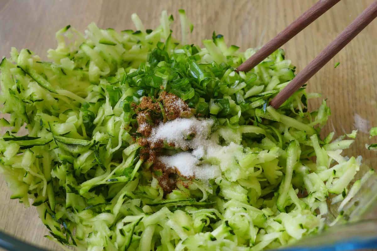 adding salt and pepper to grated zucchini.