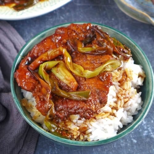 scallion pork chop over a bowl of rice.