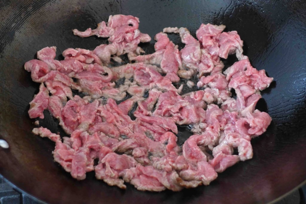 searing beef strips in a wok.