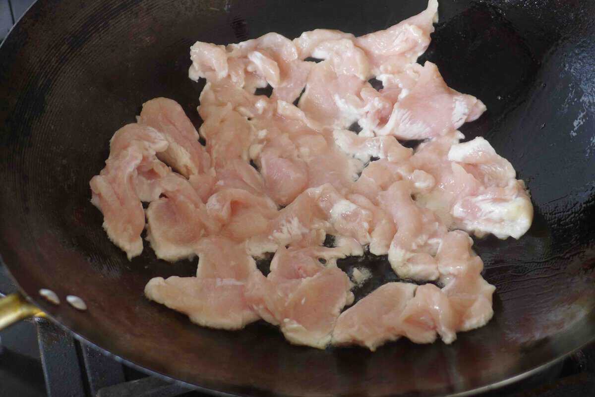 chicken slices in a wok.