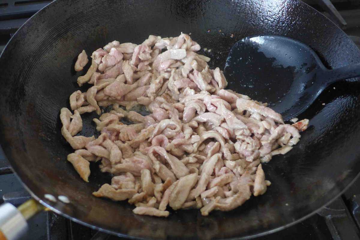 searing pork in wok.
