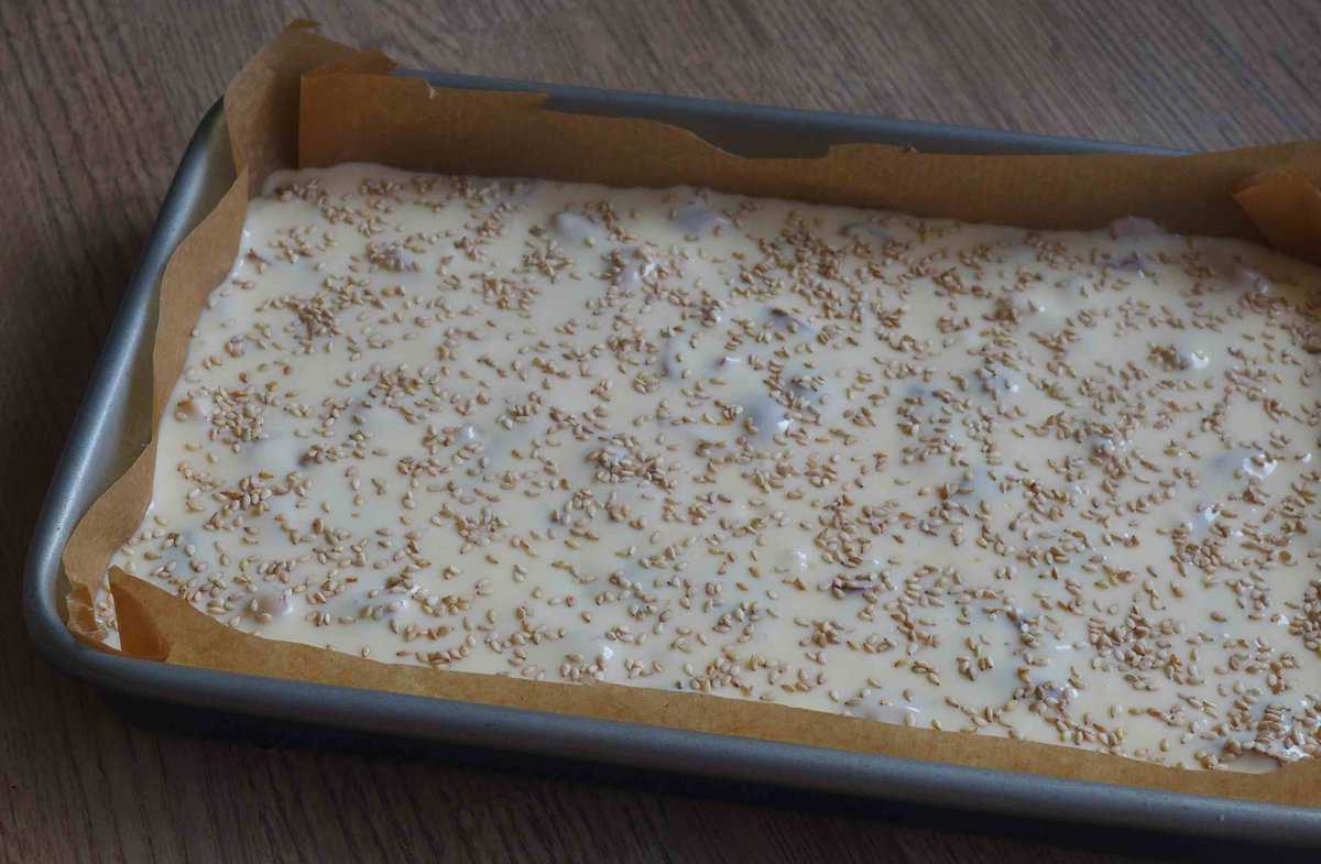 sesame seeds over cake batter in a baking dish.