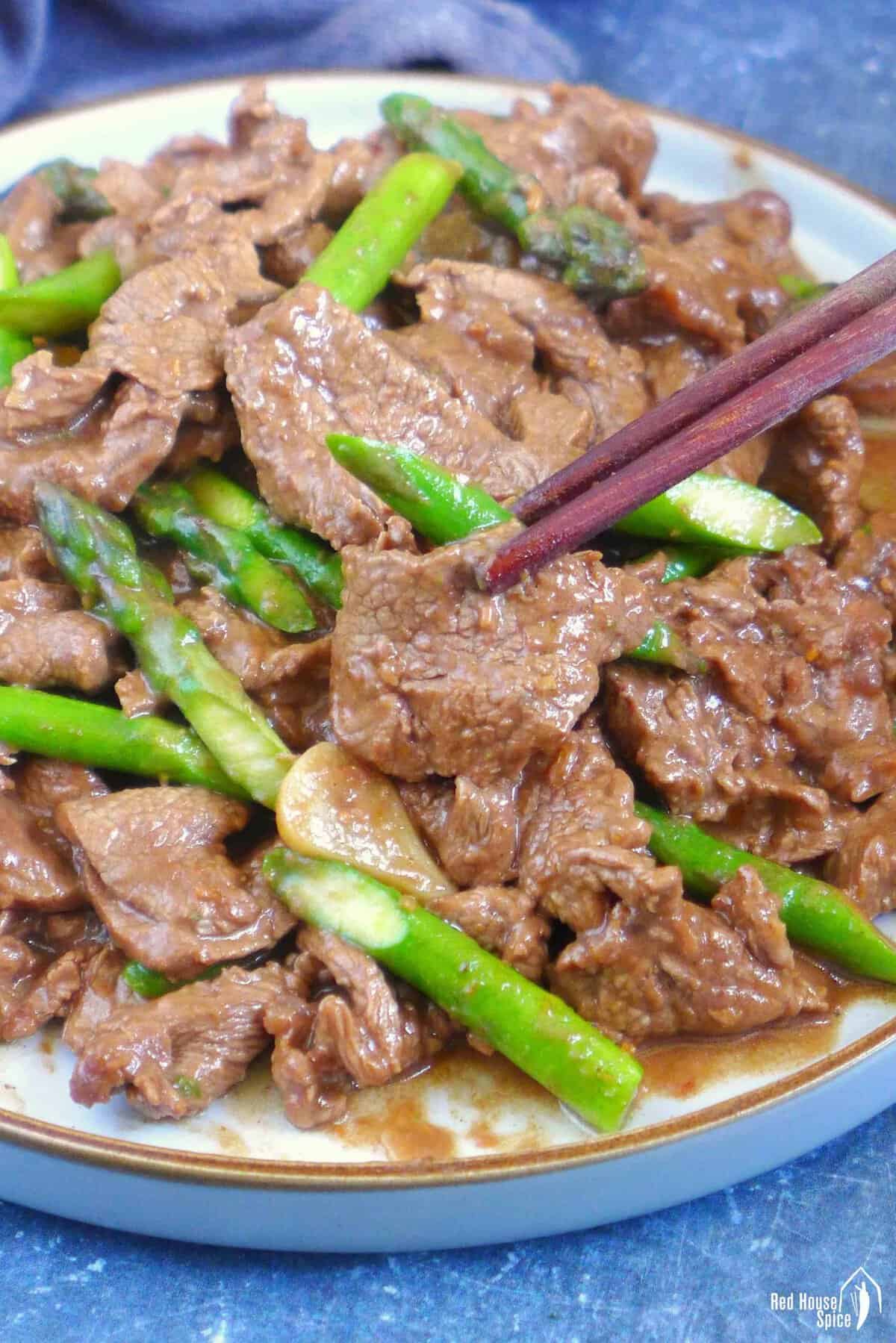 chopsticks picking up a piece of beef.