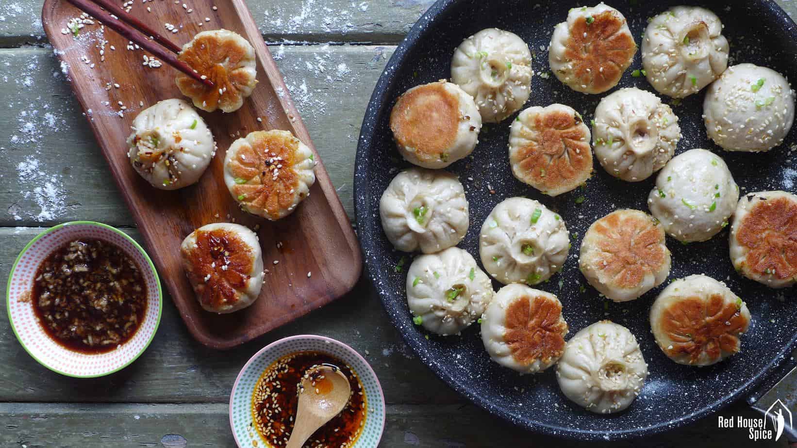 Sheng Jian Bao (pan-fried pork buns) in a plate and in a frying pan.