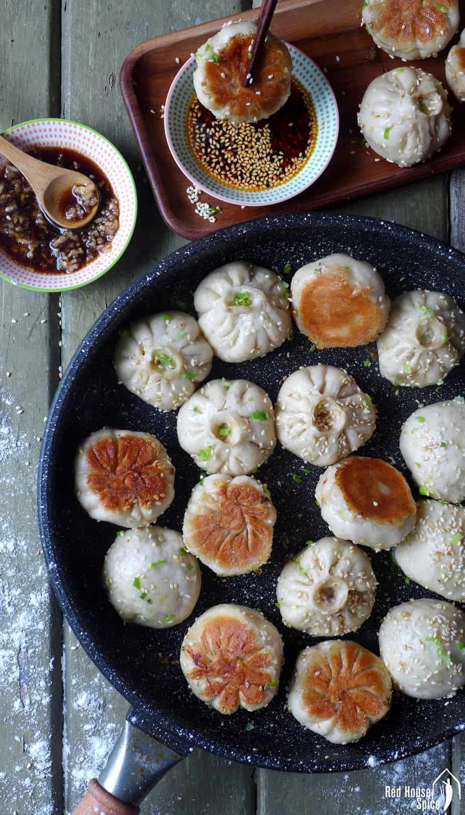 Sheng Jian Bao (pan-fried pork buns) cooked in a black frying pan.