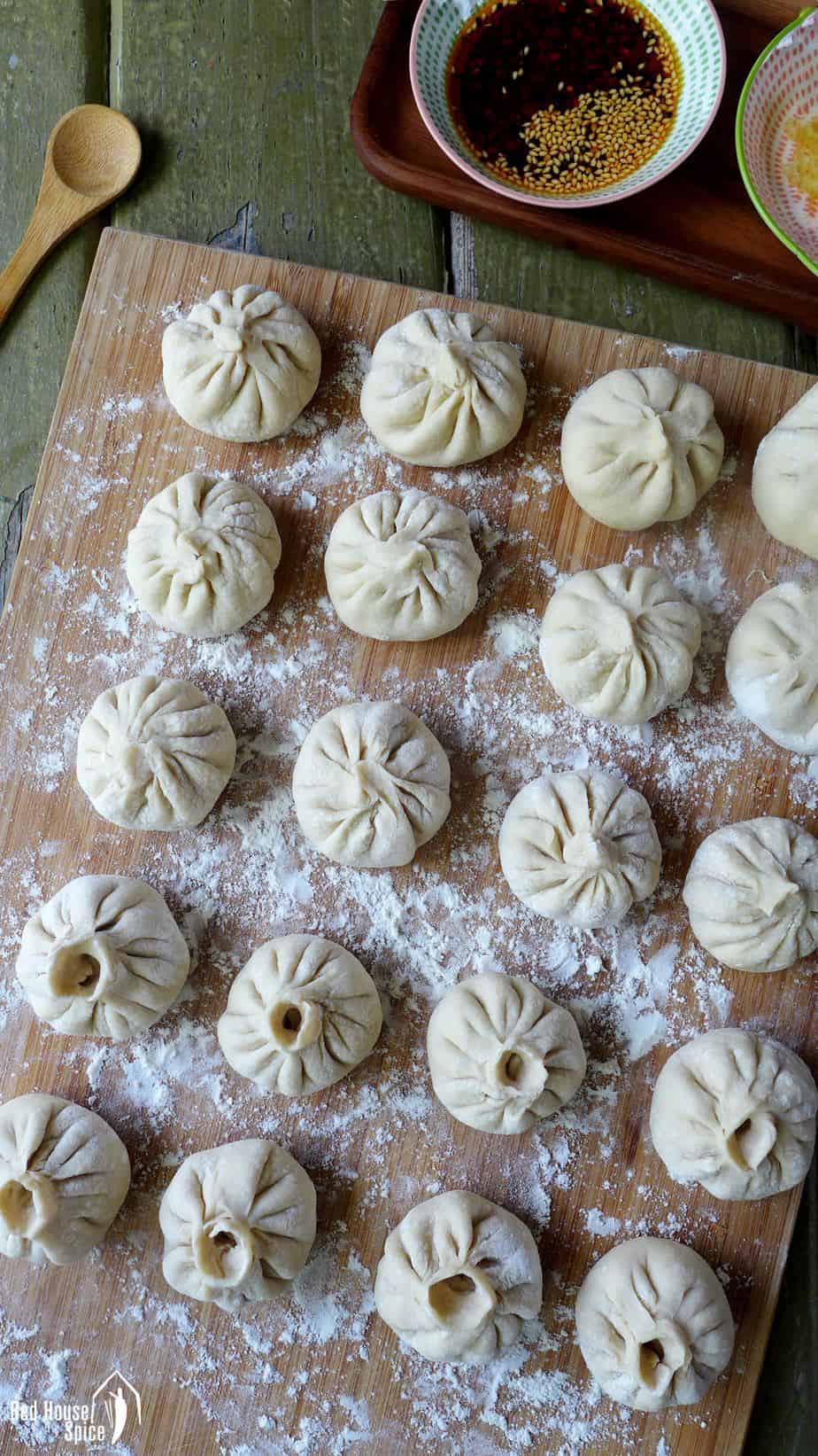Freshly assembled Sheng Jian Bao (pan-fried pork buns) on a chopping board ready to be cooked.
