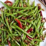 A plate of fried beans with overlay text that says Sichuan green beans.
