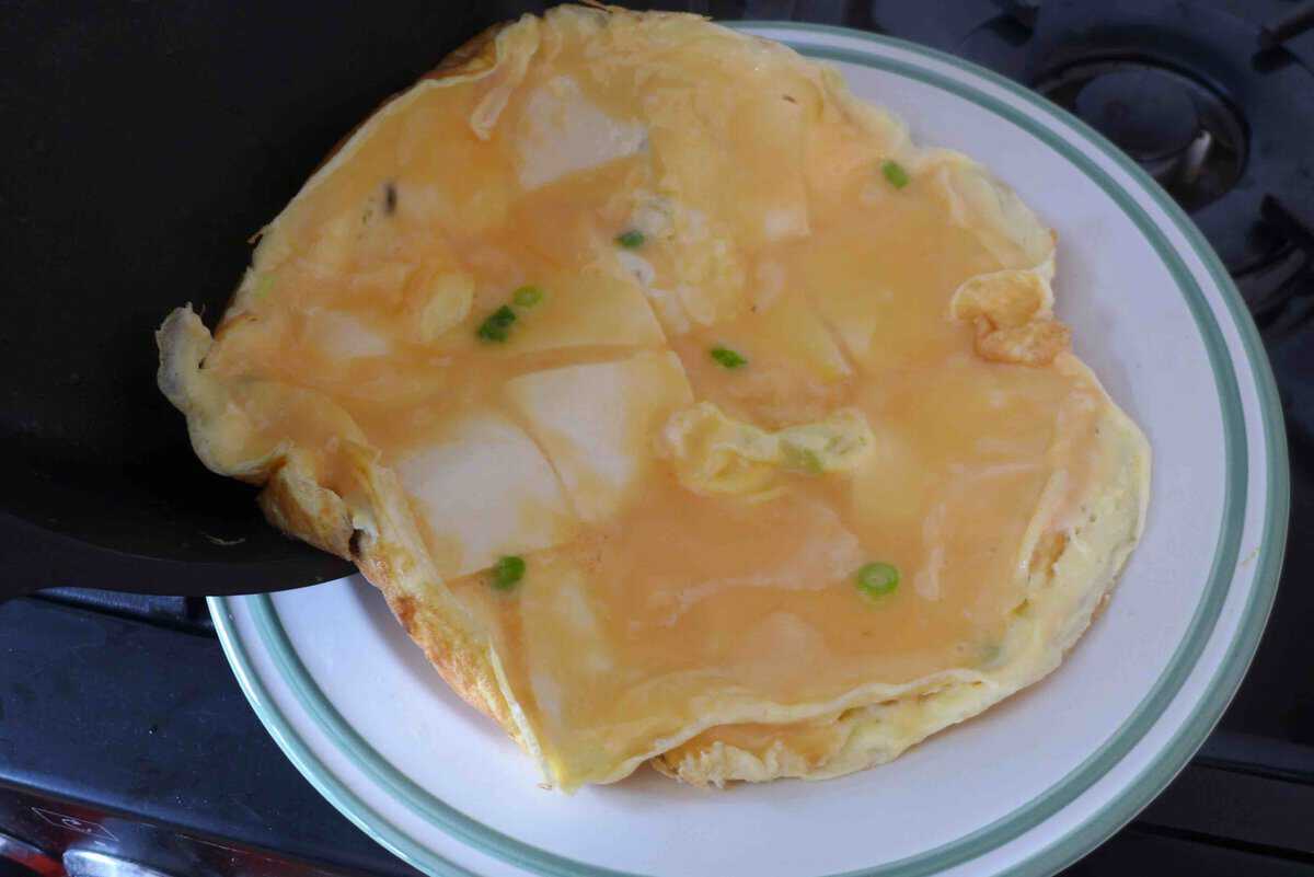 transfer a half-cooked omelet onto a plate.