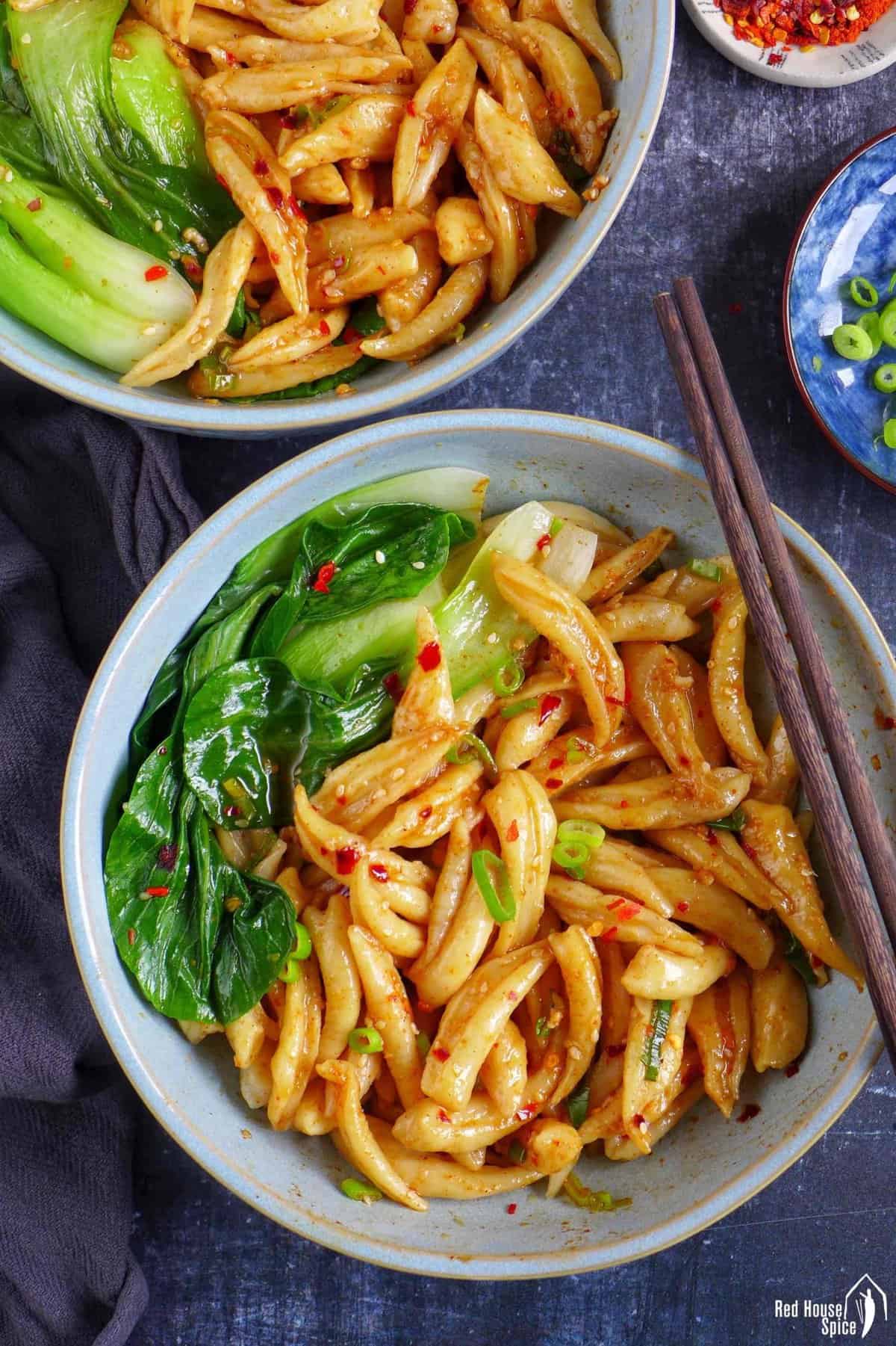 Two bowls of scissor cut noodles with Bok Choy