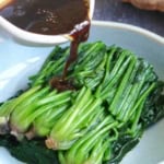 pouring sauce over blanched spinach.
