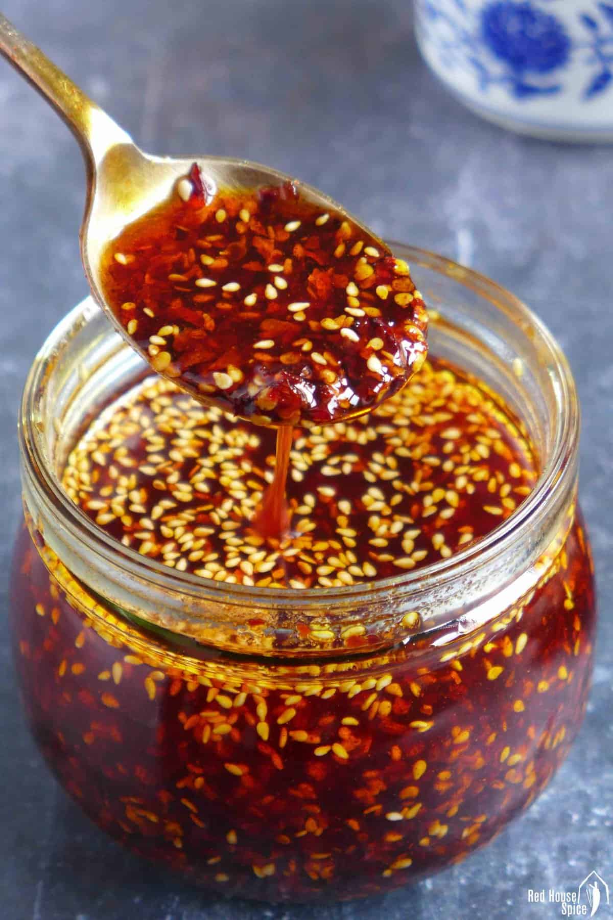Chili oil in a spoon over a jar.