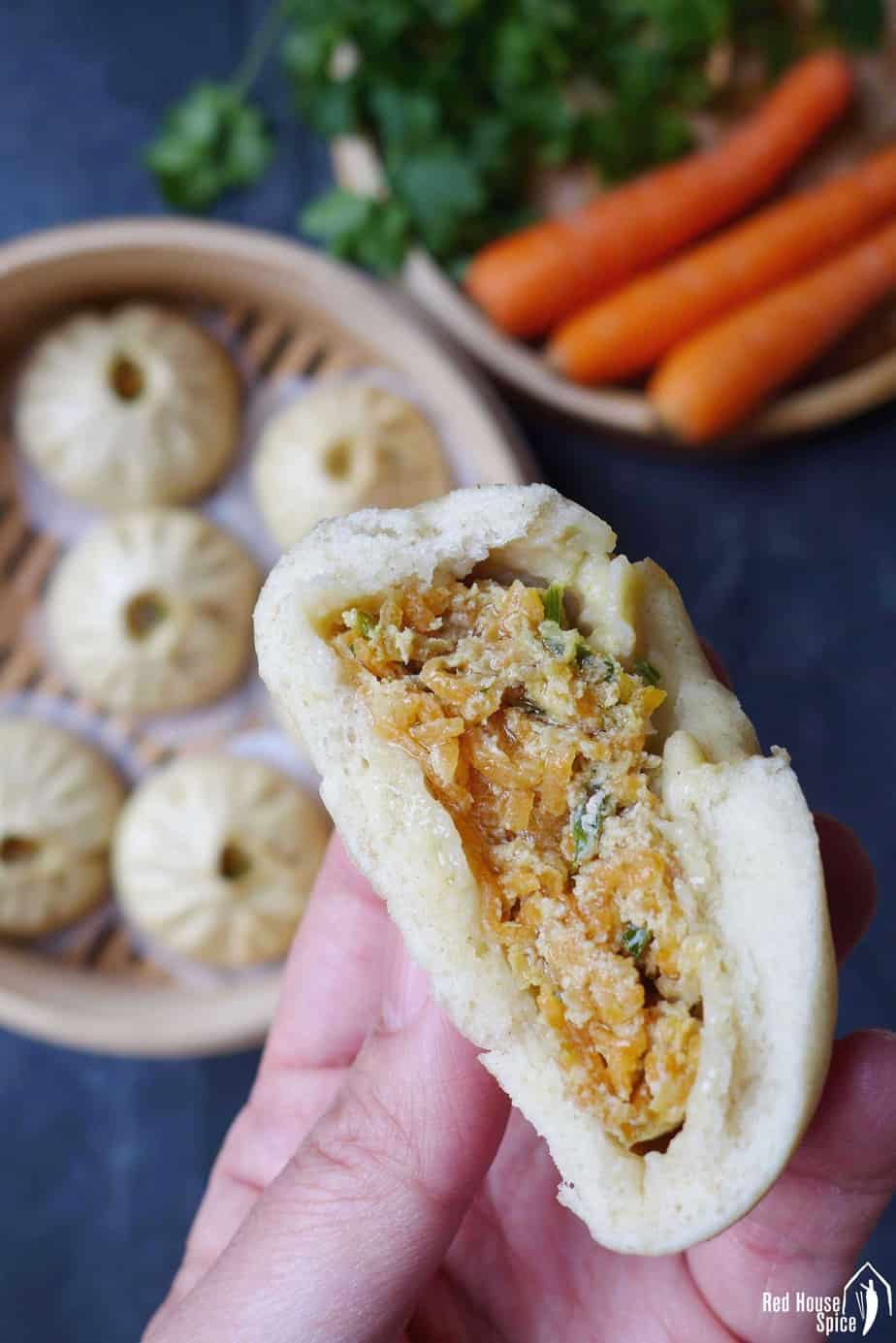 A half eaten steamed bao bun showing the meat & veggie filling.