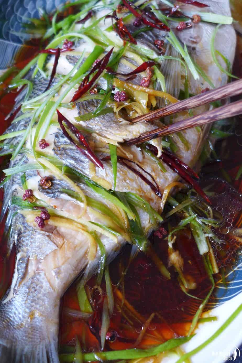 Picking up a piece of steamed fish with chopsticks