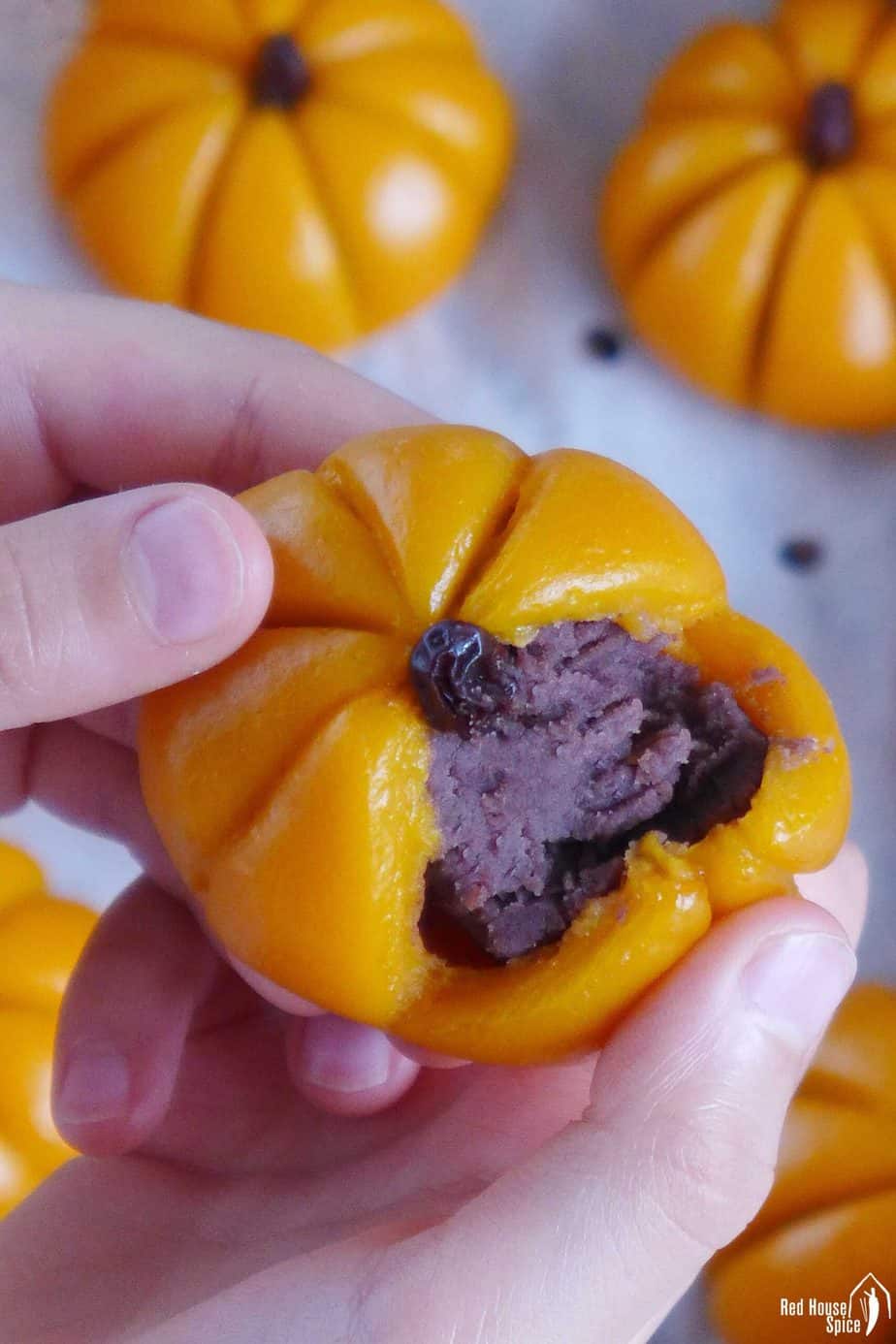 A sticky rice pumpkin cake torn open showing its red bean paste filling.