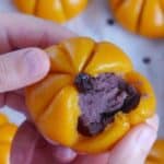 A pumpkin mochi cake torn open showing its red bean paste filling.