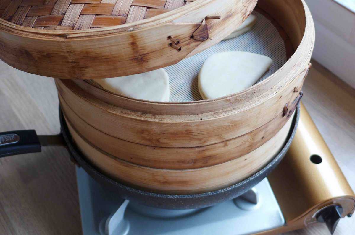 steaming bao buns in a bamboo steamer.