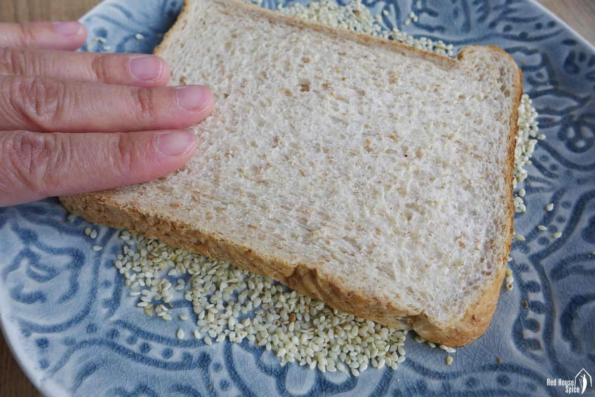 Pressing a piece of toast over sesame seeds.
